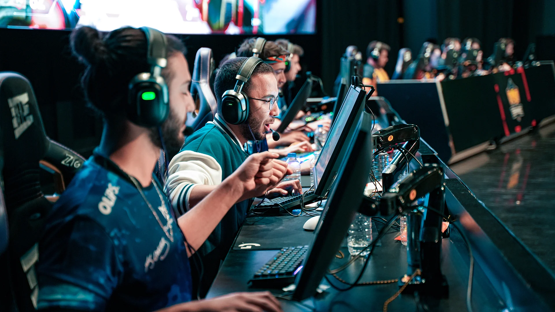 Professional esports players wearing tournament headsets and exchanging short tactical calls during a match